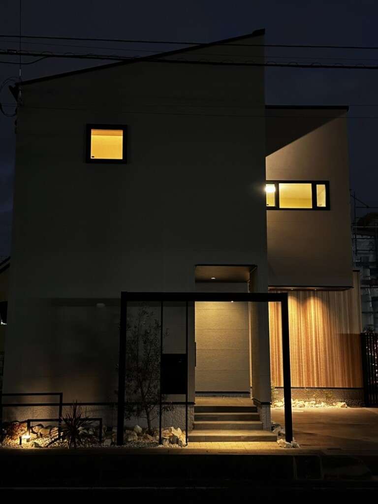 夜間にライトアップされたYKKリレーリアフレームゲートと植栽のアプローチ