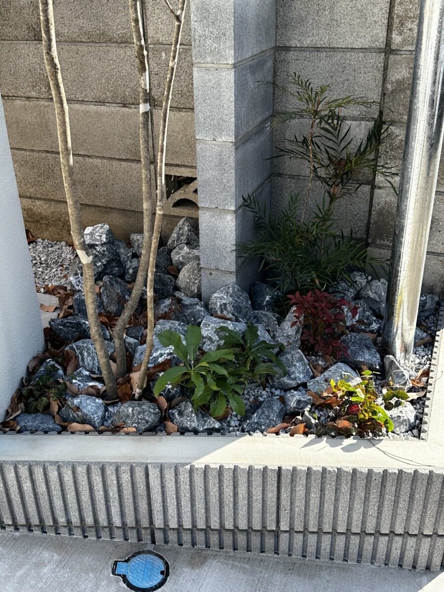 門周りの花壇に据えられた大きめの自然石と、足元を彩る植栽。