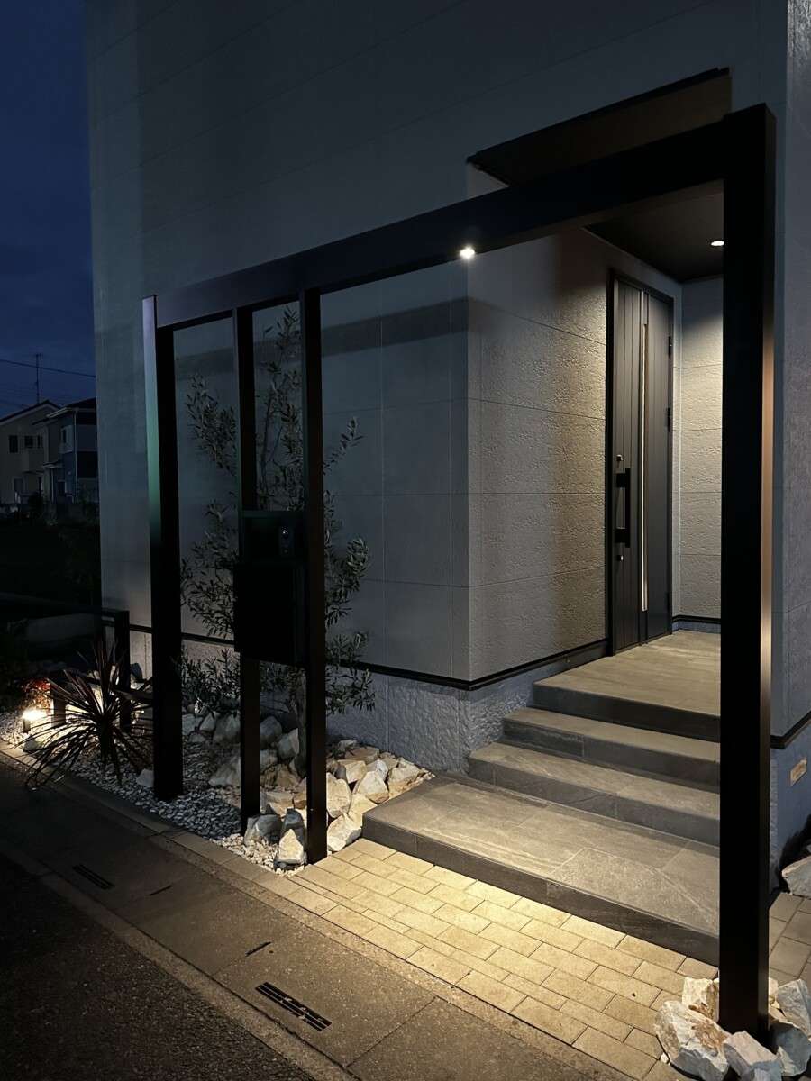 夕景のエクステリア全景。建物と一体感のあるフレームと植栽の配置