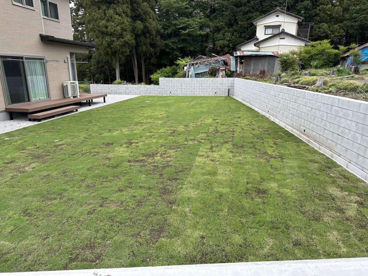 人工木ウッドデッキと芝生を設置した広々とした庭