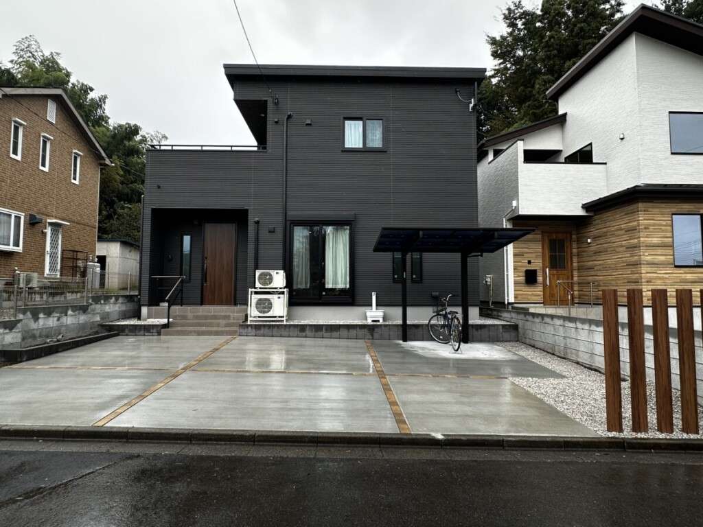 ブラックの外観が映える新築住宅と広々とした土間コンクリートの駐車スペース
