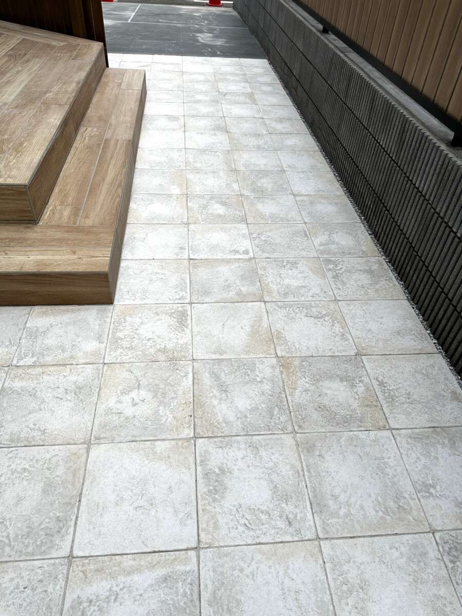 石目調の床タイルと木目調デッキのコントラストが美しい、メンテナンスフリーなガーデンスペース。