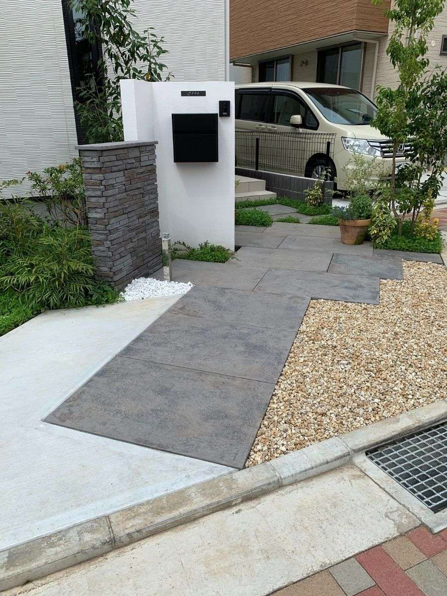 ラッジウォールを貼った門柱と植栽が印象的な玄関まわり。斜め配置で視線をやさしく遮る設計。