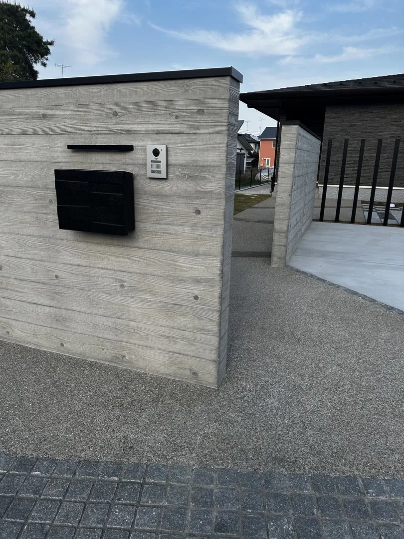 門塀と玄関アプローチの全体像。洗い出し仕上げの床面と浮造り門塀が一体感のある外構を形成
