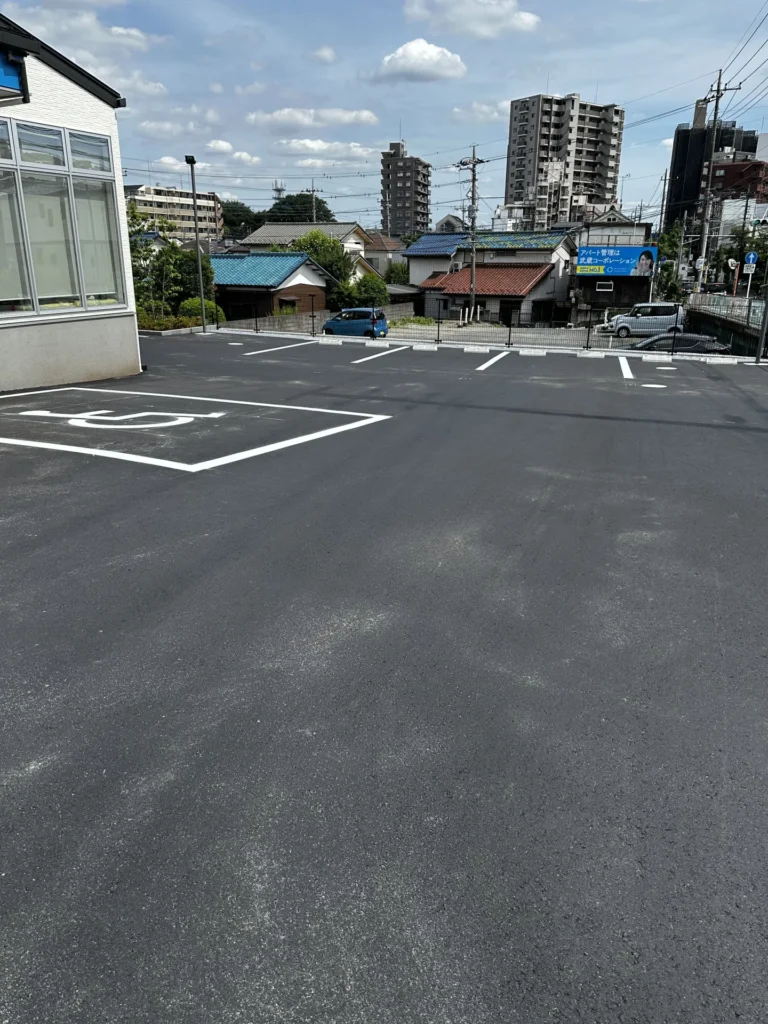 クリニック正面のアスファルト駐車場。視認性の高い白の区画線。障碍者マーク