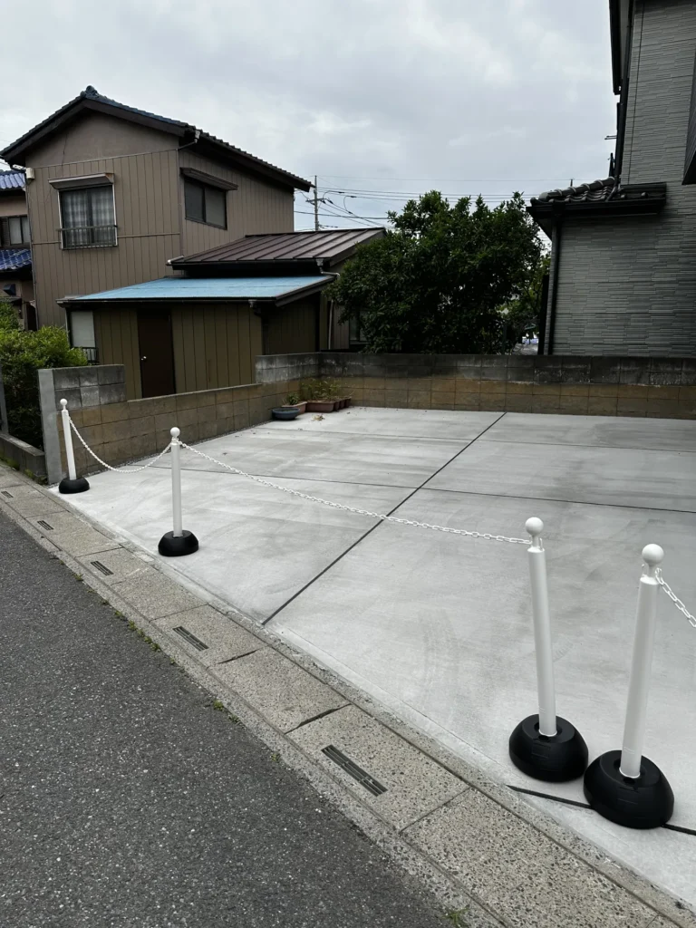 ブラックの建物と調和する土間コンクリートの駐車スペースと外構全体