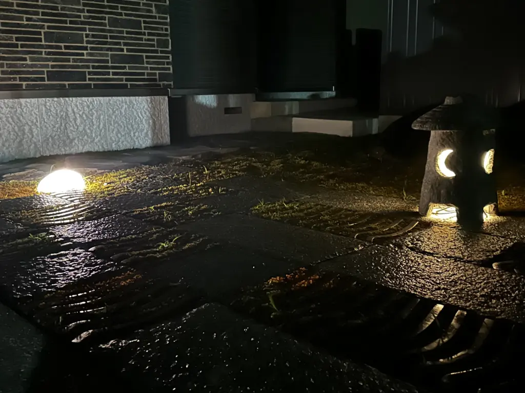 和モダン中庭の夜景。苔と自然石がライティングに照らされ、昼間とは趣の異なる静かな表情を見せる